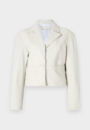 Skórzana jasnobeżowa kurtka z zapięciem na guzik, szerokimi klapami i długimi rękawami. Gładka tekstura z prostym, minimalistycznym wzorem.