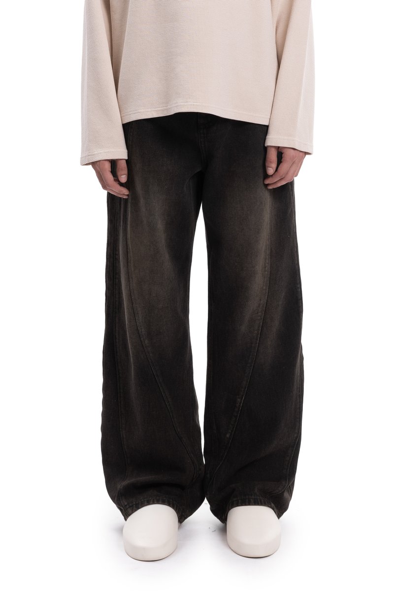 Fekete, széles szárú farmernadrág kopott hatással, íves varrásokkal és laza szabással, világos színű hosszú ujjú felsővel párosítva.