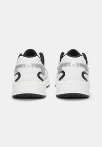 Białe i czarne sportowe sneakersy z teksturowanym wzorem, gładkimi powierzchniami, przezroczystymi akcentami oraz gumową podeszwą z bieżnikiem.