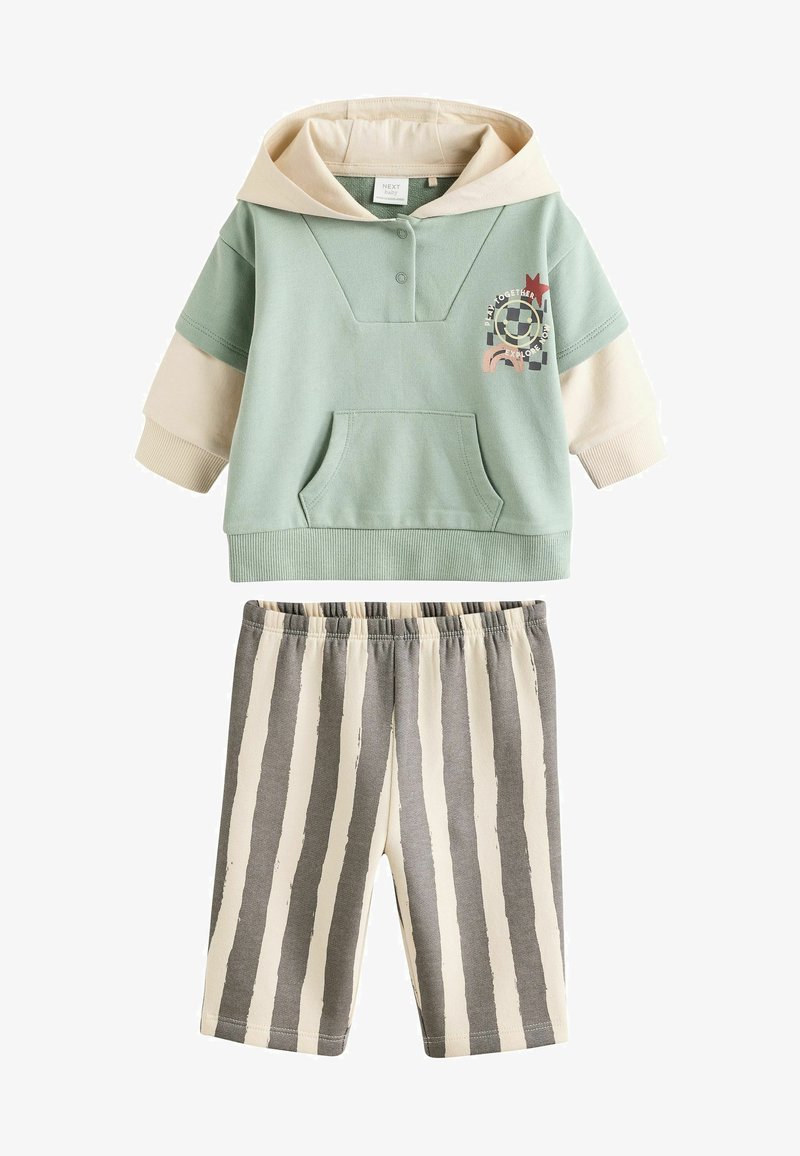 Mentazöld kapucnis pulóver, krémszínű részletekkel és elülső zsebével, szürke és krémszínű csíkos rövidnadrággal párosítva. Puha pamutkeverék.