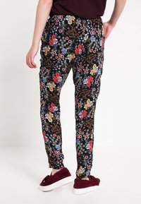 Floral-patterned trousers with a black background, featuring multicolored flowers. Made of lightweight fabric, tapered design, and elastic waistband.