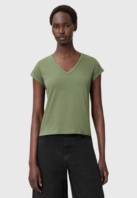 Grøn bomulds T-shirt med V-hals og korte opslåede ærmer; afslappet pasform. Kombineret med sorte bukser, minimalistisk design og blød tekstur.