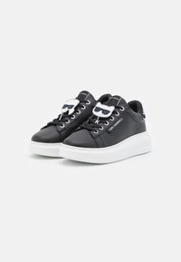 Sneakers in pelle nera con suola platform bianca, caratterizzate da accessori argentati e dettagli a forma di occhiali da sole sui lacci che catturano l'attenzione.