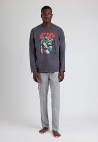 Camisa gris de manga larga con un gráfico colorido de "Star Wars". Pantalones de pijama grises con un patrón que presenta un diseño geométrico repetido.