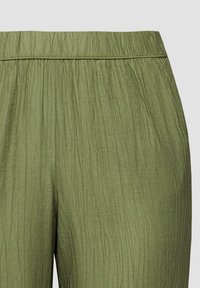 Pantalon vert olive avec une texture froissée et une taille élastique.