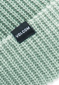 Knitted beanie in a light mint green color, featuring a textured pattern and a black label with "VOLCOM" printed in white.