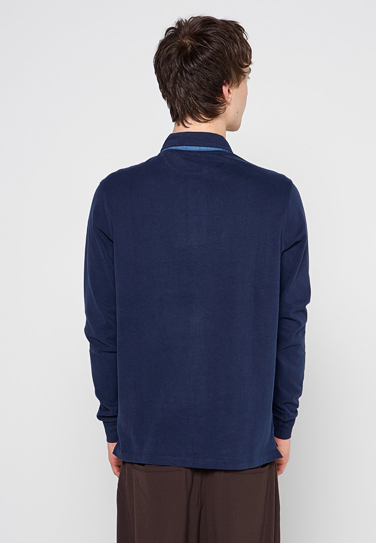 Marineblaues Langarmshirt mit glatter Textur, featuring einem einfarbigen Kragen und Rückendetails, das eine lockere Passform bietet.