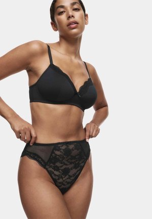 Reggiseno in pizzo nero e slip a vita alta abbinati, con motivo floreale, bordi smerlati e dettagli in rete. Texture complessivamente liscia.