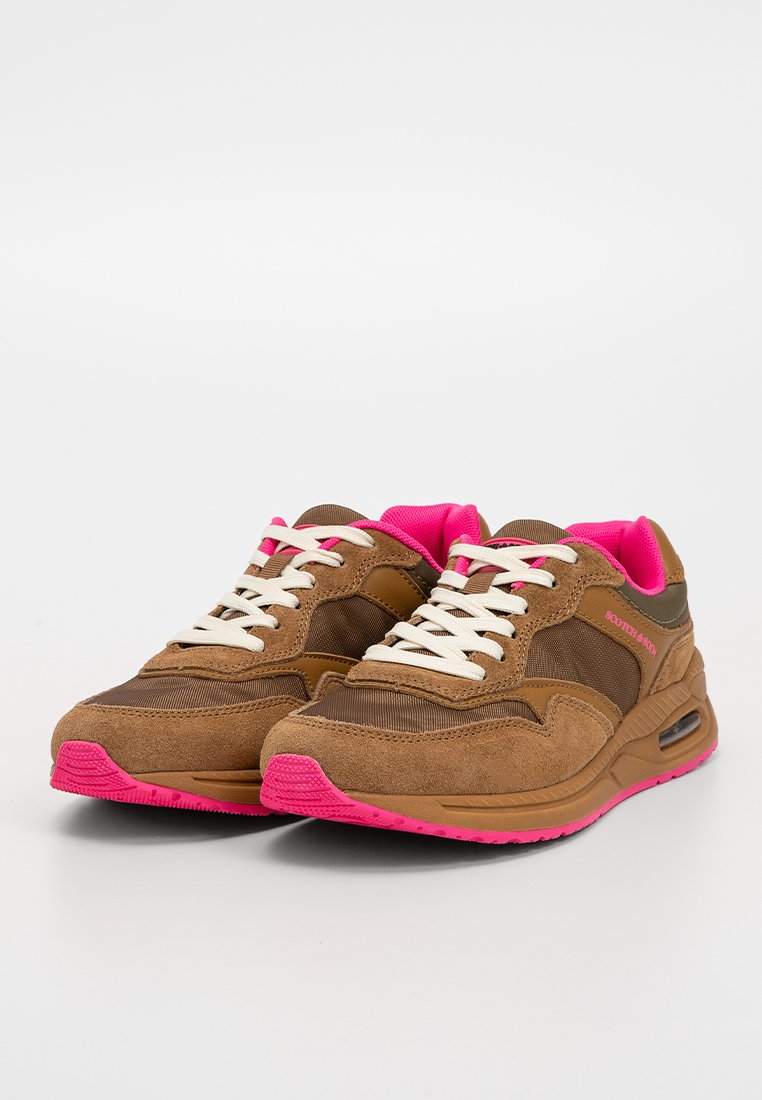 Zapatillas deportivas marrones y rosas con cordones blancos, acentos de gamuza y suelas acolchadas, colocadas una al lado de la otra sobre un fondo blanco.