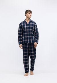 Conjunto de pijama de franela de cuadros en azul marino que incluye una camisa de botones y pantalones con cintura elástica, con acentos en cuadros azul claro y rojo.