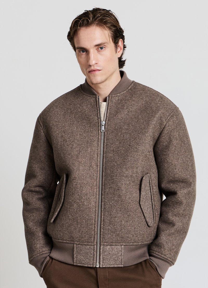 Braune Bomberjacke aus Wollmischung mit Reißverschluss vorne, Strickbündchen und zwei Seitentaschen. Verfügt über einen abgerundeten Kragen und eine strukturierte Oberfläche.