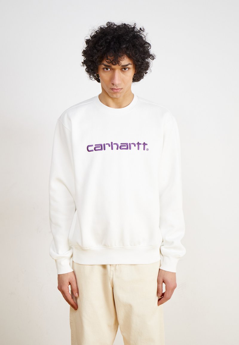 Fehér pulóver bordázott mandzsettákkal és aljjal, az előoldalon egy feltűnő lila "carhartt." logóval. Simaság jellemzi az anyag textúráját.