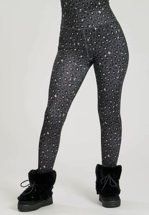 Zwarte en grijze legging met luipaardprint, gemaakt van rekbare stof, met een hoge tailleband en een zachte afwerking. Gecombineerd met zwarte laarzen met bontvoering.