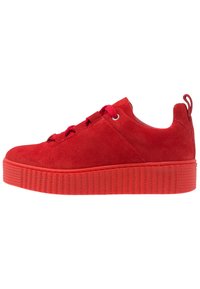 Baskets en daim rouge avec une semelle en caoutchouc épaisse et texturée. Comprend des lacets ronds, des œillets en métal et une languette à l'arrière. Fini lisse.