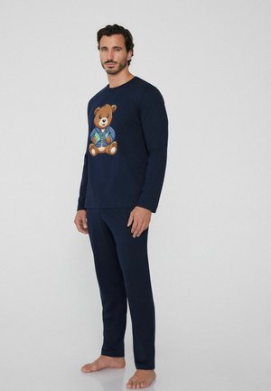 Navy long-sleeve pajama set features a cartoon bear graphic on the shirt. Soft fabric with fitted pants, no visible patterns or hardware.