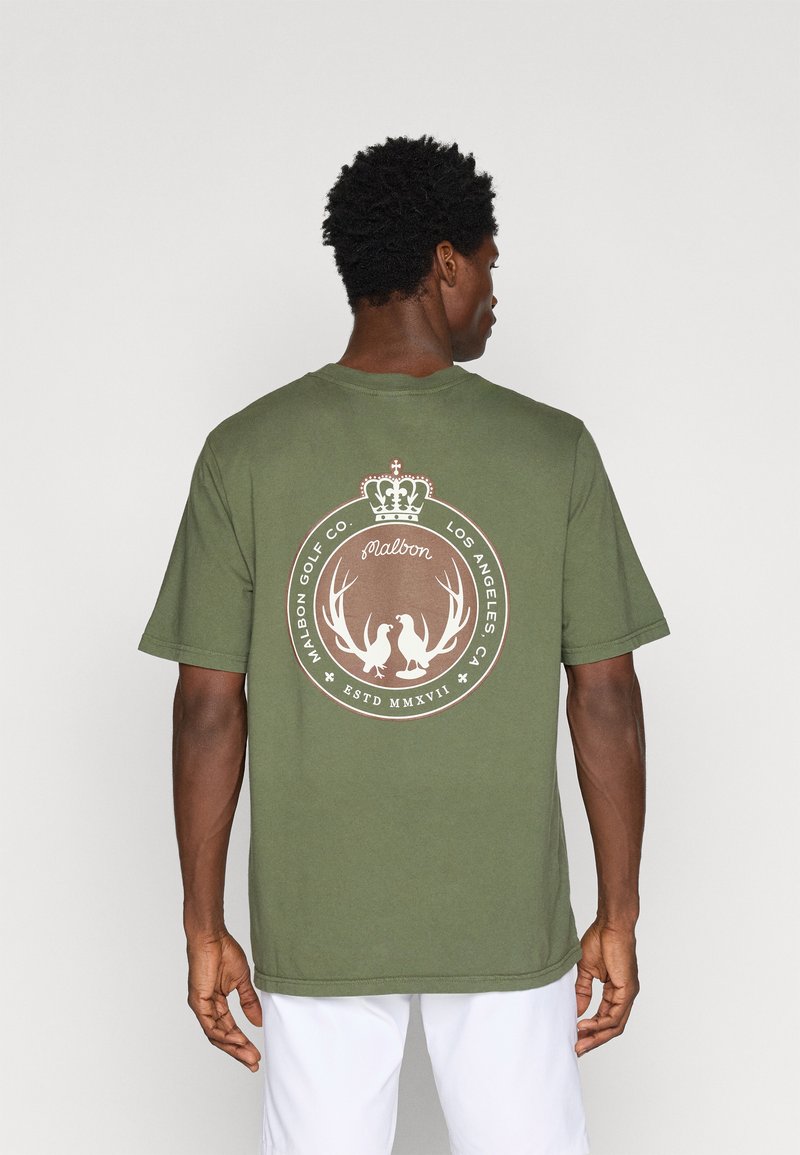 Oliņzaļš kokvilnas T-krekls ar apļveida logotipu brūnā krāsā, kurā attēlota kroņa un raga simbolika, kā arī teksts. Īsas piedurknes un brīvs griezums.