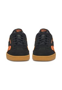 Crne i narančaste Reebok tenisice s gumenim potplatima, prikazane sprijeda, s vezicama i logom na jeziku i stranama.