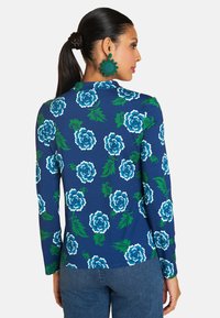 Navy long-sleeve top featuring a floral pattern in blue and green, made of soft fabric with a rounded neckline and fitted design.
