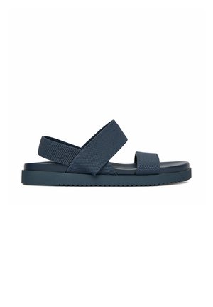 Marineblaue flache Sandale mit zwei breiten Stoffriemen über dem Fuß und Knöchel, strukturierter Sohle und gepolstertem Fußbett, gezeigt auf weißem Hintergrund.