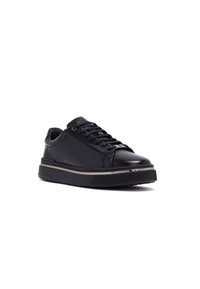 Sneaker in pelle nera con lacci piatti, punta rotonda, colletto imbottito e suola in gomma a contrasto con una striscia accentata orizzontale.