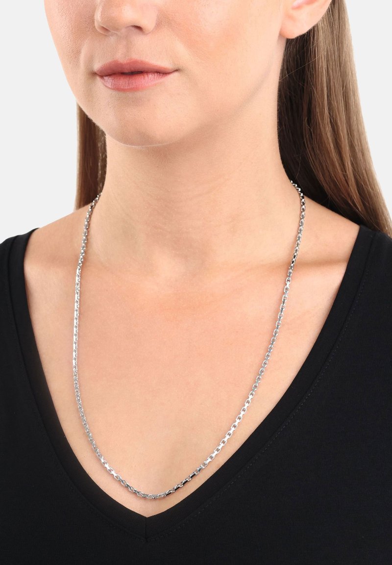 Silver kedja halsband på en person, med släta, sammanlänkade länkar. Bärs över en svart V-ringad topp.