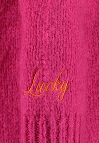 Gestrickter Pullover in leuchtendem Pink mit einem gerippten Muster, versehen mit einem orangen "Lucky" Stickdetail auf der Vorderseite.