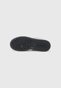 Suela de sneaker de goma negra con patrones de tread circulares y lineales, que presenta un logo central de Nike y una superficie texturizada para mayor agarre.