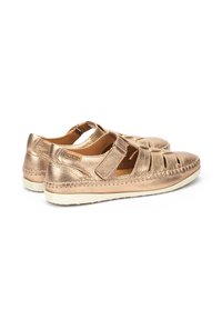 Sandalias metálicas doradas con diseño recortado, correa ajustable, forro suave y suela blanca en contraste. Detalles cosidos a lo largo de los bordes.