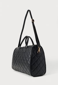 Μαύρη τσάντα χειρός από καπιτονέ ύφασμα με διπλές επάνω λαβές και αποσπώμενο ιμάντα ώμου. Διαθέτει εξαρτήματα σε χρυσό τόνο και δομημένο, στρογγυλεμένο σχήμα.
