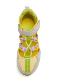 Chaussure de sport jaune et grise avec tissu texturé, élastique et accents verts ; présente des lacets violets et jaunes et une semelle intérieure rembourrée.