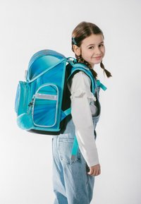 Tyrkysový batoh s lesklým povrchovým úpravou, mnoha kapsami a huňatým modrým bambulíkem. Obsahuje polstrované popruhy a módní tvar.
