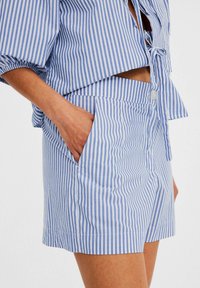 Blå och vit randiga bomullsshorts med en slät textur, med sidfickor och en välavslutad fåll.