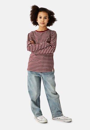 Red and gray striped long-sleeve shirt with round neckline, paired with light blue baggy jeans and white sneakers. Crossed arms pose.