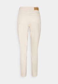 Beige Hose mit schmaler Passform, denimähnlicher Textur, fünf Taschen und einem hellbraunen Lederpatch an der Taille. Sanfter, leichter Stoff.