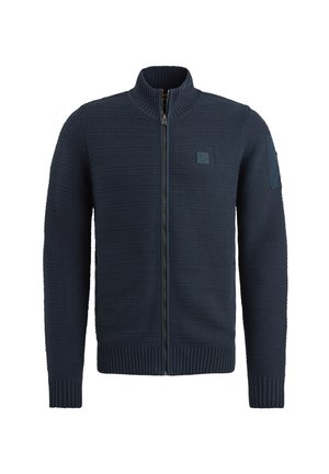 Pull en jersey zippé bleu marine avec un col montant, des poignets et un ourlet côtelés, un motif tricoté texturé, et un détail en patch sur la manche gauche.