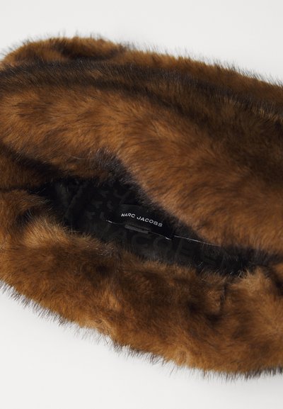 Kunstpels hodebånd i rik brunfarge med en myk tekstur. Det indre foringslaget har merkevarenavnet, Marc Jacobs, på en svart bakgrunn.