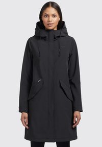 Parka nera impermeabile con cappuccio, zip frontale e due tasche laterali. Presenta coulisse regolabile e una texture liscia e opaca.