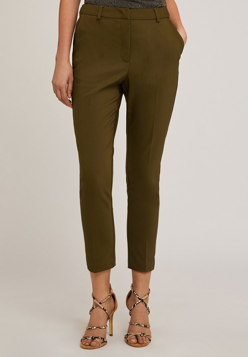 Oliwkowe, dopasowane spodnie z paskiem, z wąskim krojem, z pętelkami na pasek i bocznymi kieszeniami. Połączone z nagimi obcasami na paskach.