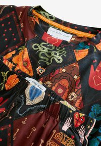 Viacfarebná látka s prepracovanými vzormi, vrátane kvetov, tvarov a motívov. Okrúhly výstrih a detail s nariaseným lemom. Jemná textúra.