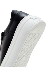 Sneaker in pelle nera con suola in gomma bianca. Presenta un design elegante, dettagli testurizzati sulla parte superiore e una chiusura con zip laterale.