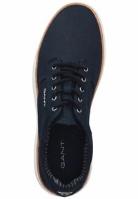 Sneaker in tela blu navy con punta rotonda, suola in gomma bianca e dettagli in pelle marrone. Presenta lacci neri e interno strutturato.