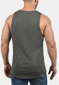 Grå tanktop med en let tekstureret stof, rund halsudskæring og en afslappet pasform, vist fra ryggen med synlige sømme og kantdetaljer.