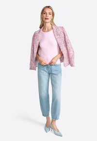 Lyserød tweedjakke over en lys lyserød ribbet top, parret med lyseblå tapered jeans og blege blå spidse hæle.