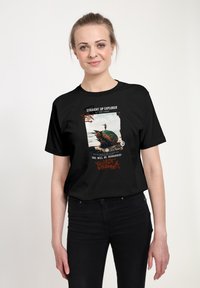 Černé bavlněné tričko s grafickým potiskem, na kterém je text a obrázek barevného objektu, ve volném střihu a s krátkým rukávem.