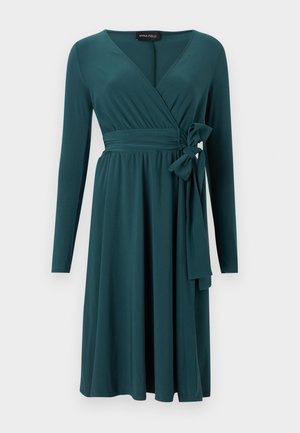 Τιρκουάζ φόρεμα τύπου wrap μέχρι το γόνατο με μακριά μανίκια, V-neckline, σφηκοφωλιά στη μέση και λεπτομέρεια φιόγκου στο πλάι.