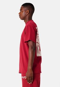 Bordeaux oversized T-shirt met korte mouwen, met grote witte tekst op de achterkant. Gemaakt van een soepele katoenmix.