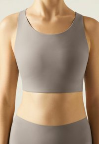 Grå sports-bralette med rund halsudskæring og brede stropper, lavet af glat, strækbart stof, designet til komfort og støtte.