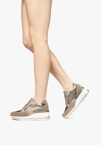 Beige und graue Sneaker mit Wildleder- und Metallic-Akzenten. Verfügt über eine dicke Sohle, Schnürdesign und eine abgerundete Zehenpartie.