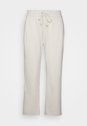 Beżowe spodnie dresowe z sznurkiem w talii, elastycznym pasem i prostymi nogawkami na gładkim tle.