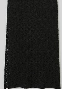 Écharpe texturée noire présentant un motif tissé avec des variations subtiles de profondeur de surface. Finition avec des bords nets et une forme rectangulaire.